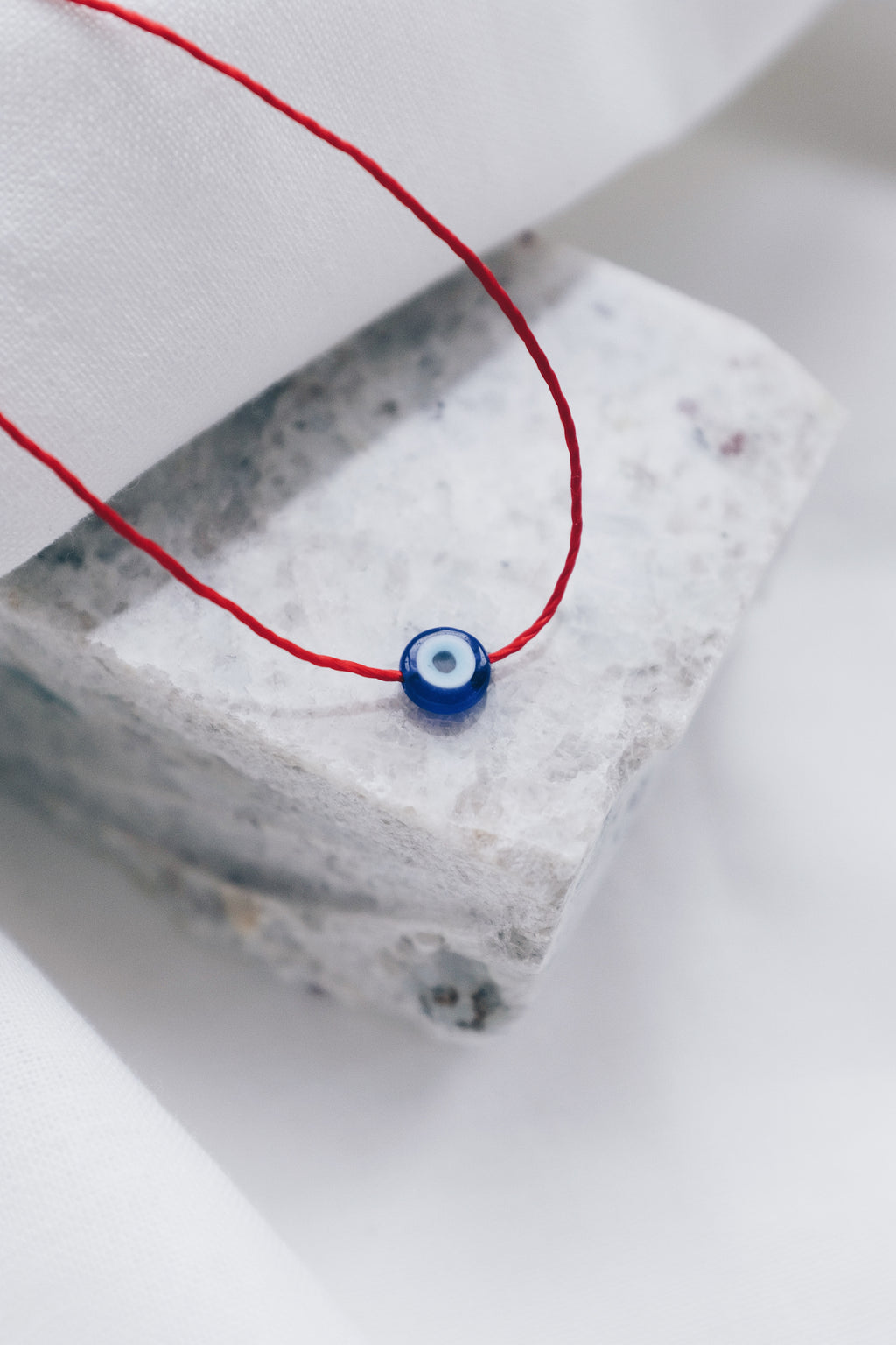 Evil eye pendant necklace on red string, symbolizing protection and warding off negative energy.