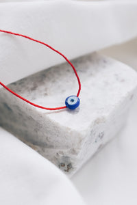 Evil eye pendant necklace on red string, symbolizing protection and warding off negative energy.