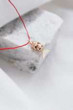 Gold fish pendant on a vibrant red chain, catching the light.