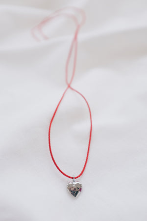 Silver ruby pendant on a red string necklace, elegant and vibrant gemstone jewelry.