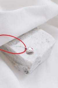 Silver ruby pendant on a red string necklace, elegant and vibrant gemstone jewelry.