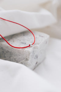 Silver tube pendant on a red string necklace, minimalist and stylish jewelry.