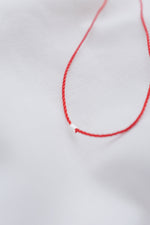 Silver tube pendant on a red string necklace, minimalist and stylish jewelry.