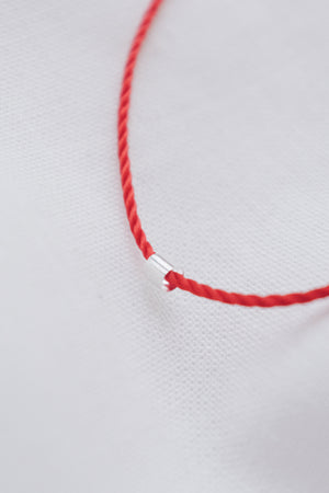 Silver tube pendant on a red string necklace, minimalist and stylish jewelry.